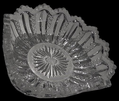 Colorless soda lime glass pressed glass square berry bowl or nappy, possibly in “Mardi Gras” pattern. Square dish, 4”. Ribbed, notched and mold seam apparent. Similar to  Duncan and Sons #42 “Mardi Gras” (1890-1910). 18CV13